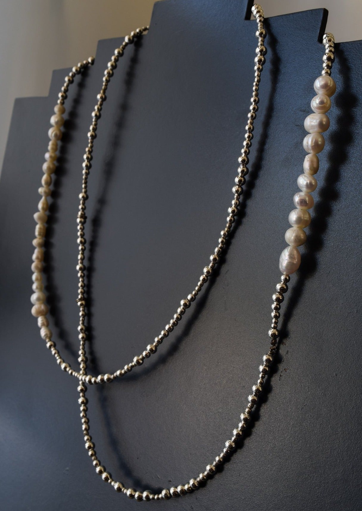 Sophisticated 36'' Necklace with Fresh Water Pearls and Silver Beads shown dabbled on a display