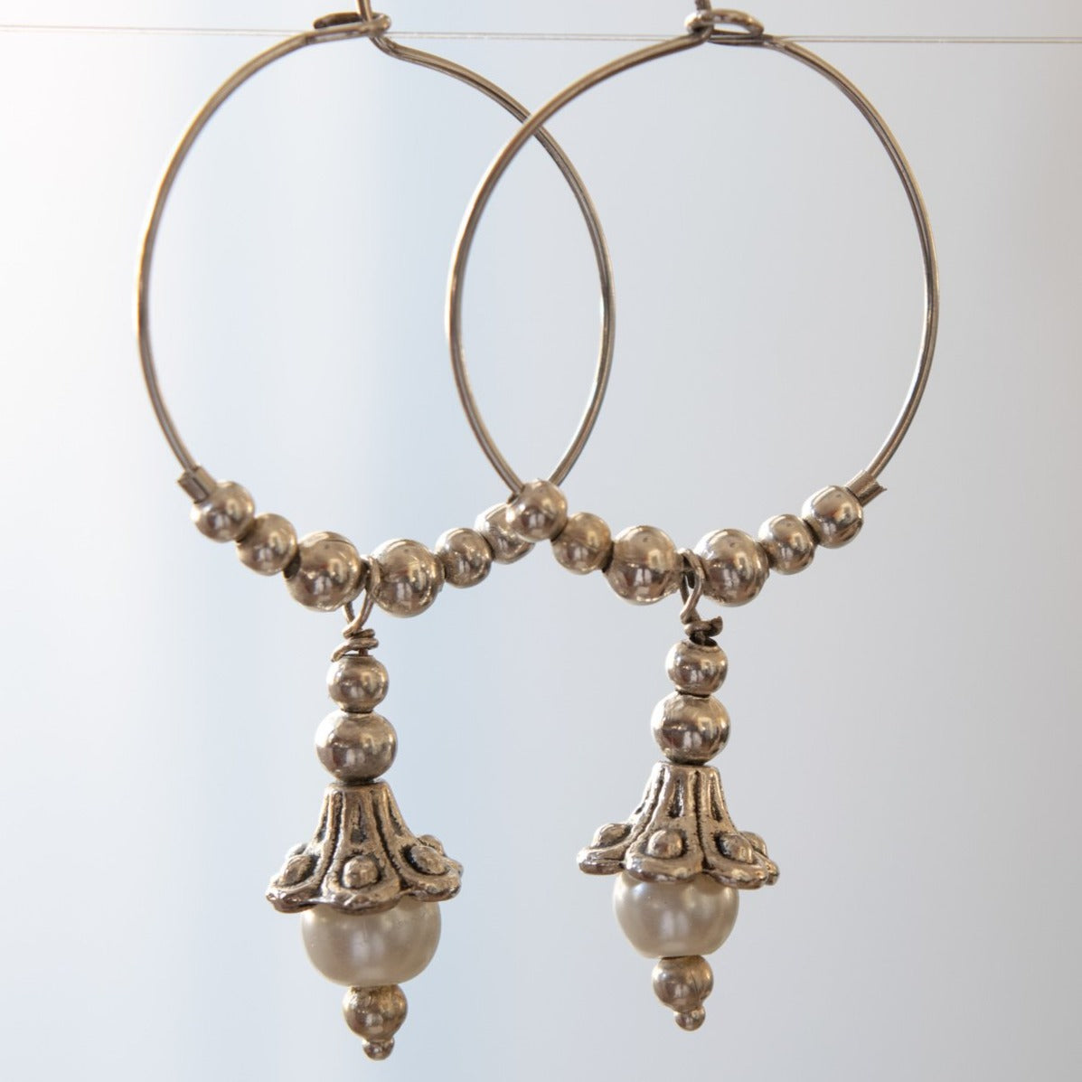 Pearls dangle hoop earrings feature a 1-inch hoop with silver beads, and a silver lily with a fresh-water pearl in the end of its bell.  Overall length is approximately 1-3/4-inch.