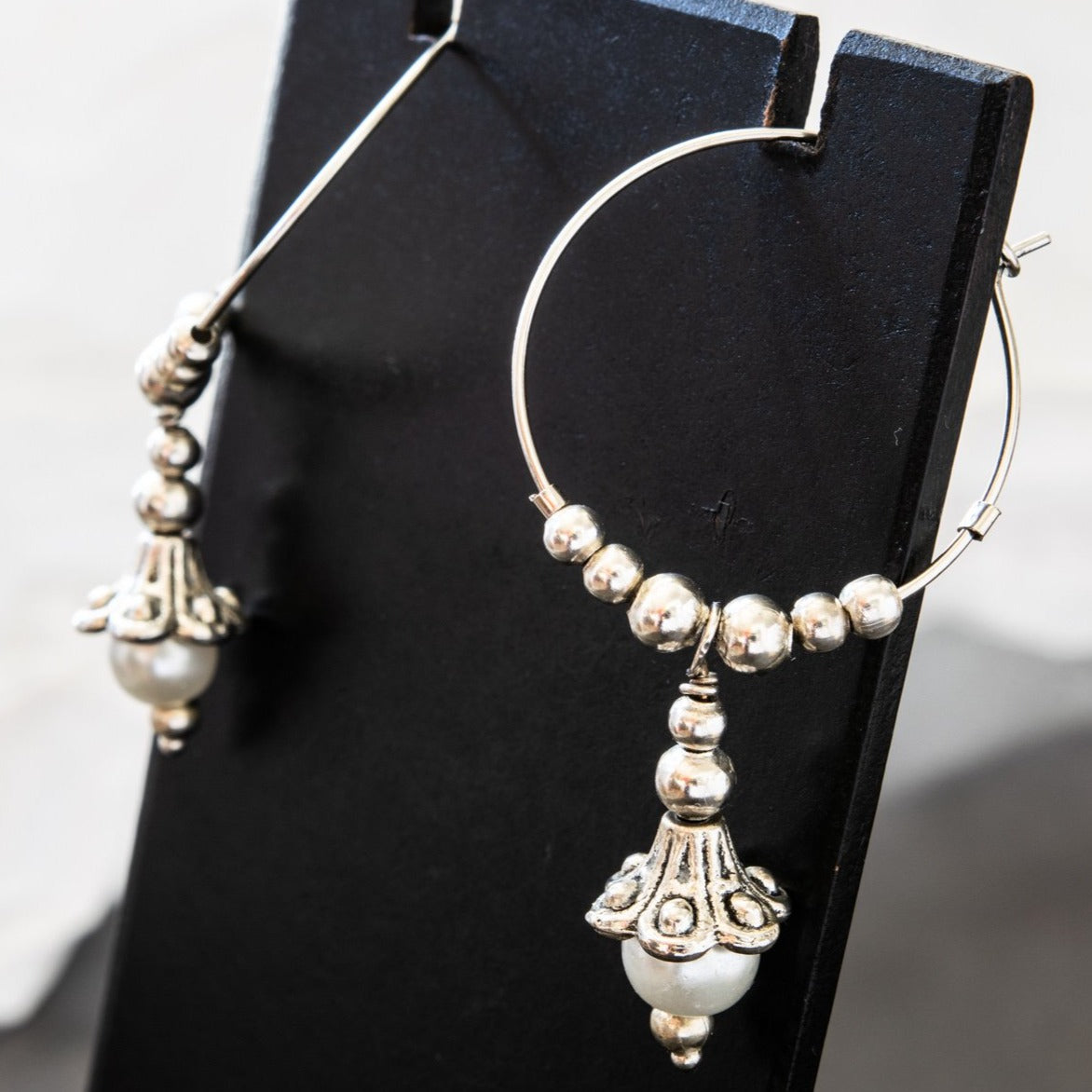 Pearls dangle hoop earrings feature a 1-inch hoop with silver beads, and a silver lily with a fresh-water pearl in the end of its bell.  Overall length is approximately 1-3/4-inch.