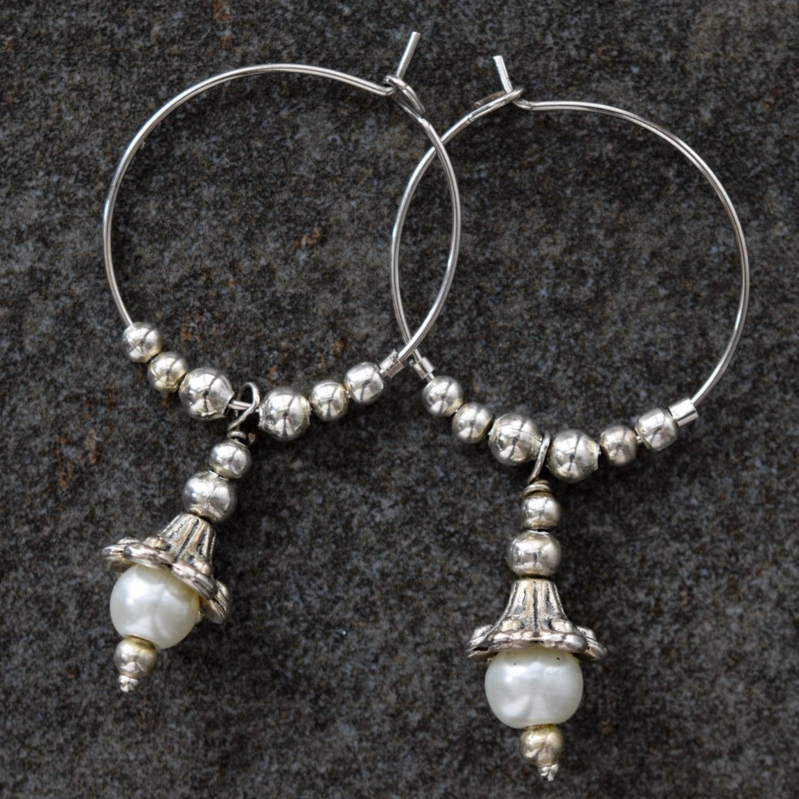 Pearls dangle hoop earrings feature a 1-inch hoop with silver beads, and a silver lily with a fresh-water pearl in the end of its bell.  Overall length is approximately 1-3/4-inch.