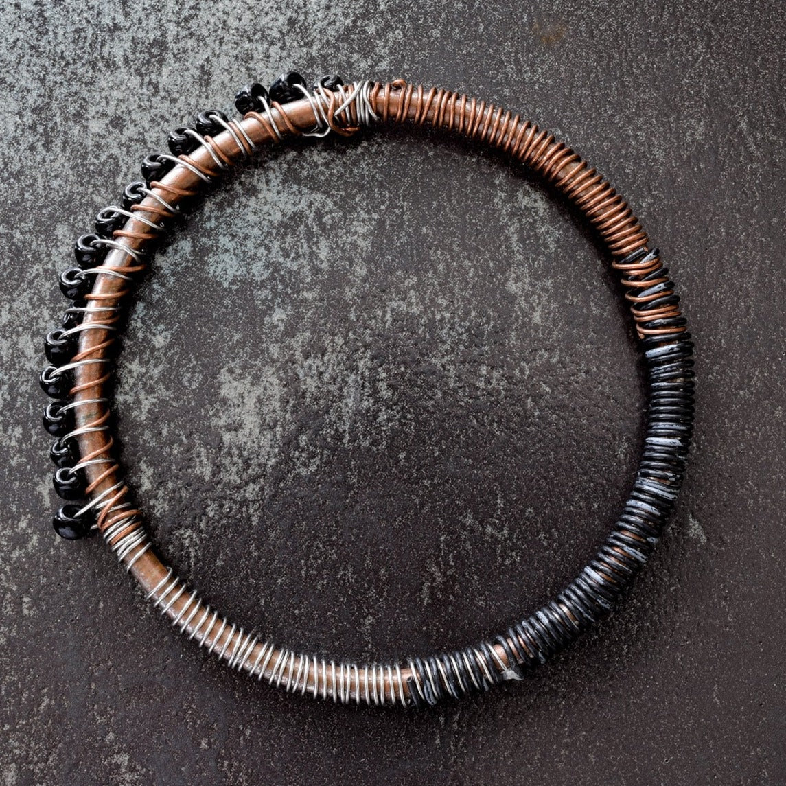 One of set of three bangles made of copper, steel and wire up cycled mixed-media