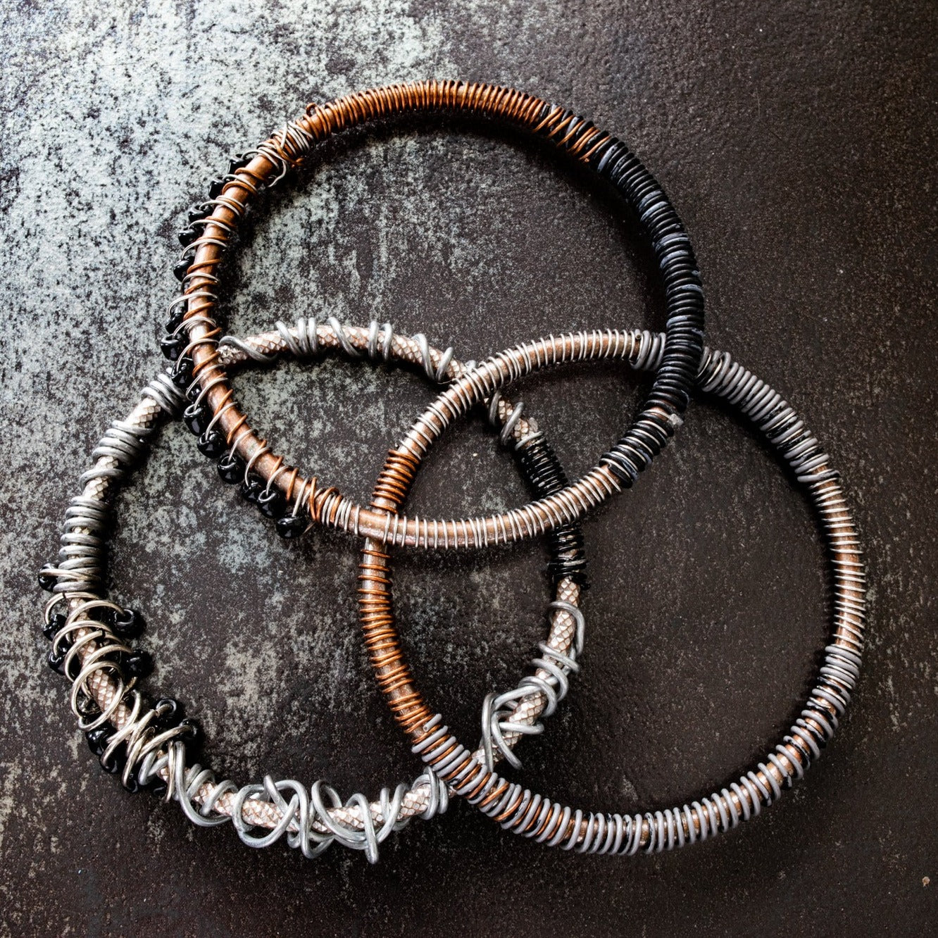 A set of three bangles made of copper, steel and wire up cycled mixed-media